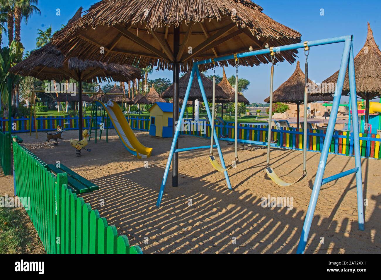 Swings frame structure in children's playground area with slide Stock Photo