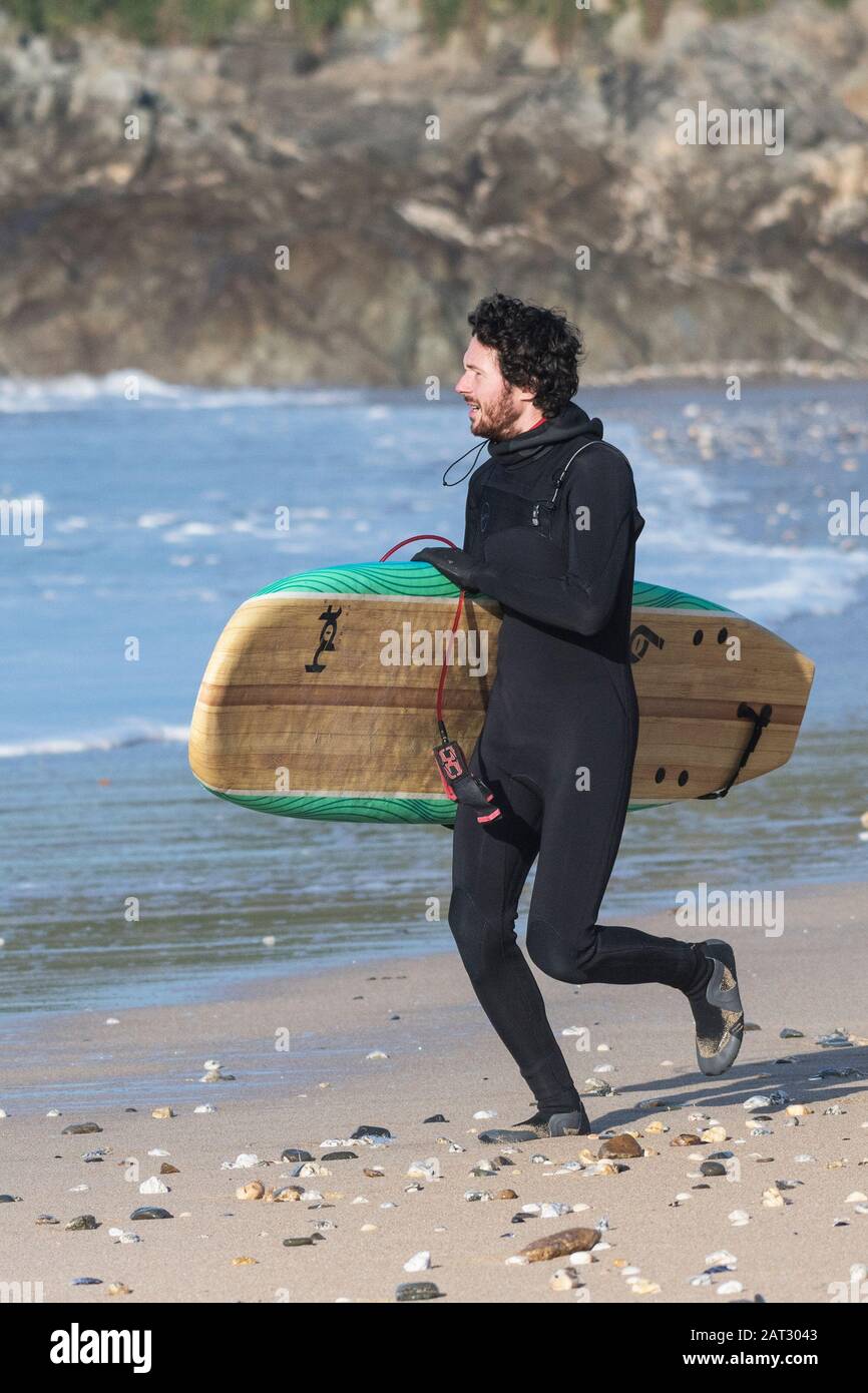 A keen surfer running towards the sea at Fistral in Newquay in Cornwall. Stock Photo