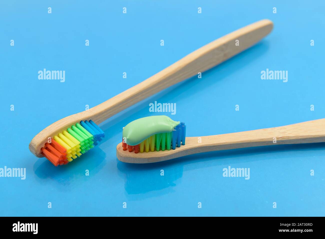Bamboo toothbrush with green toothpaste on blue background with water drops. Eco friendly concept Stock Photo