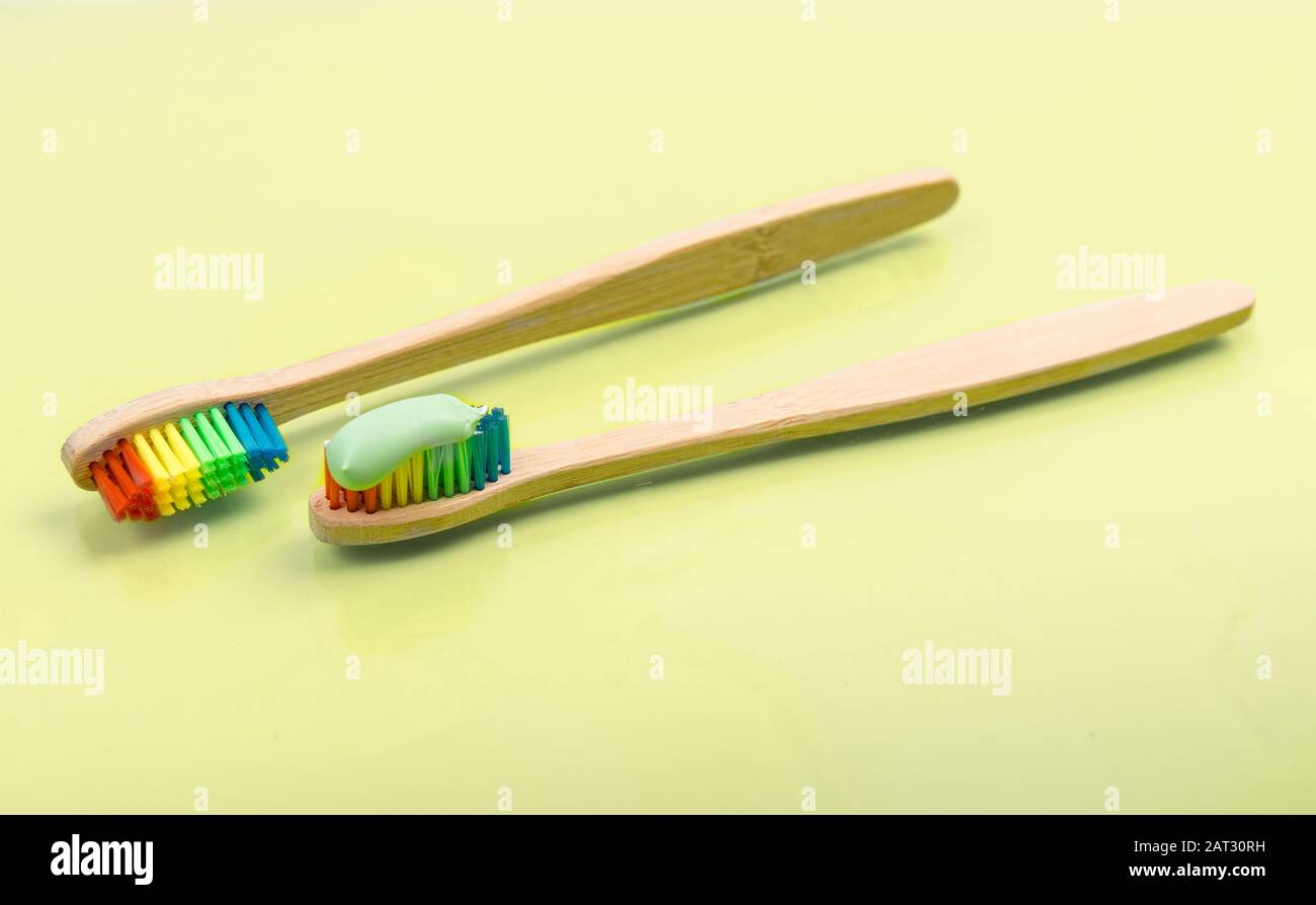 Bamboo toothbrush with eco green toothpaste on pastel background. Pair of multi-colored wooden tooth brushes Stock Photo