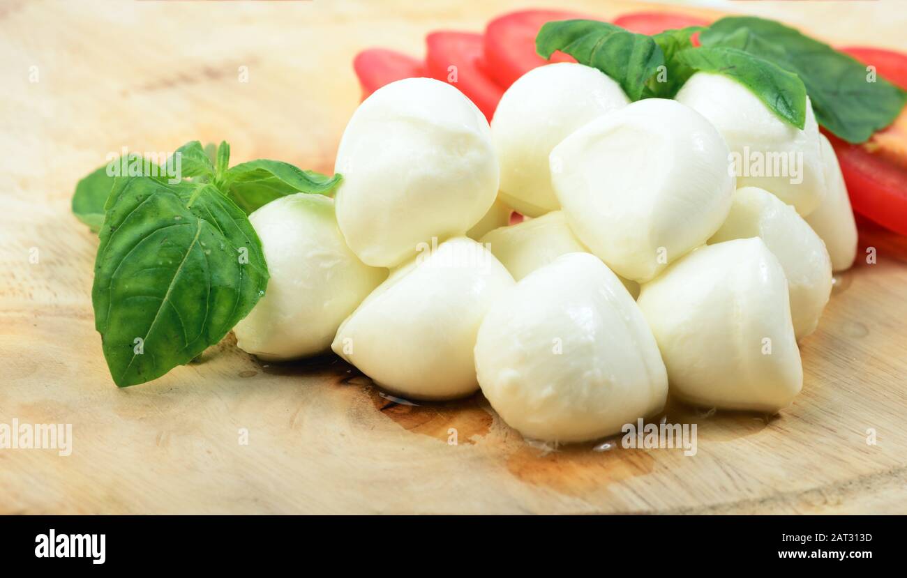 Mozzarella cheese with tomatoes and basil on wooden desk Stock Photo
