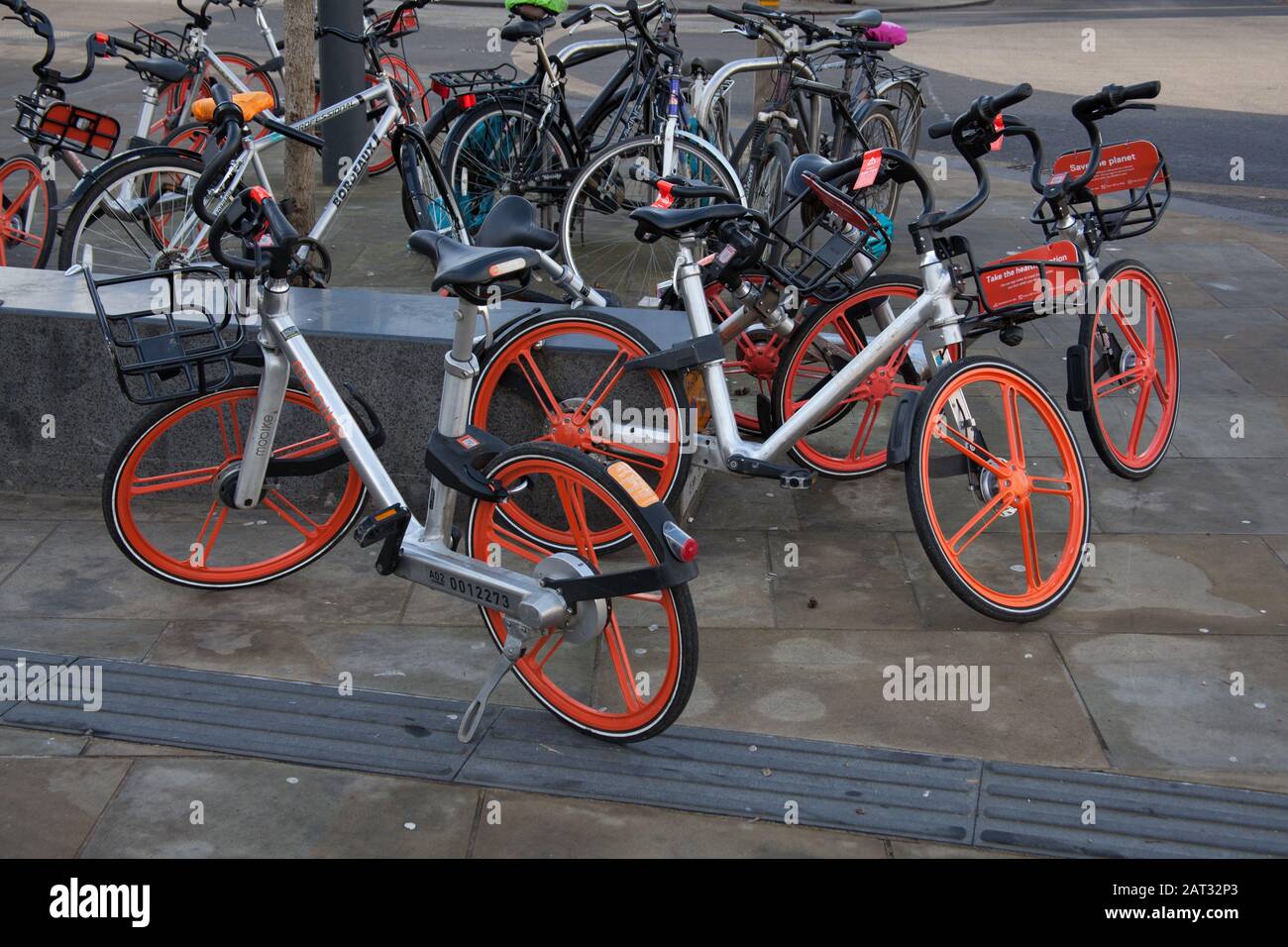 Mobikes for hire in Oxford:  Their bikes are bright metallic silver with unusual orange wheels. Stock Photo