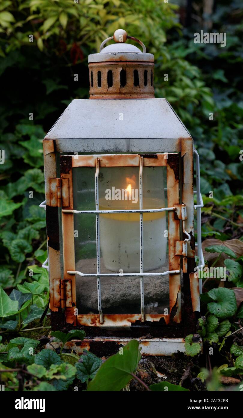 old rusty lantern with burning candle at a grave in a cemetery Stock Photo