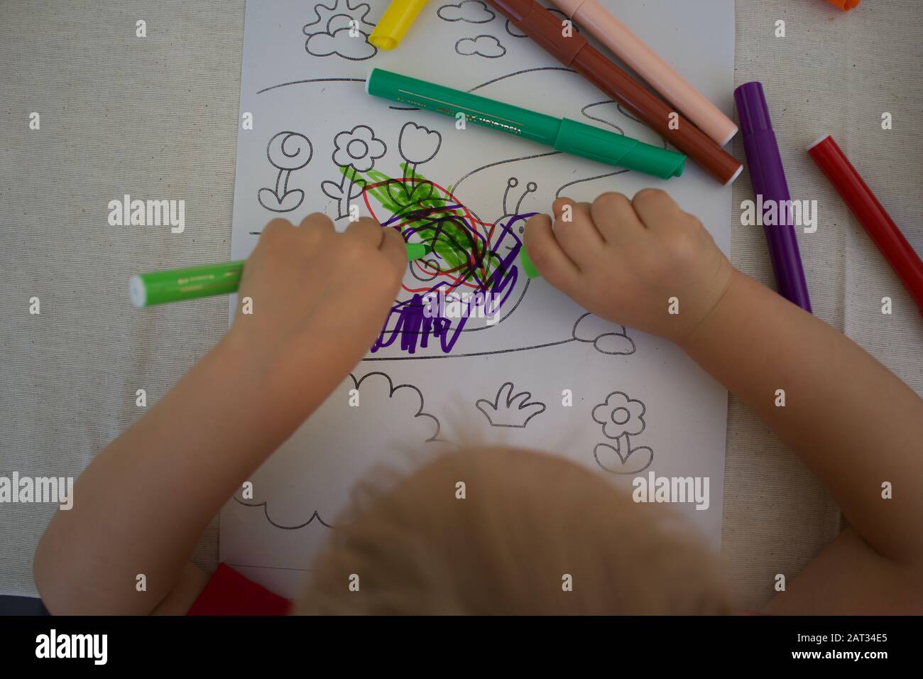 Small child drawing with colored pens - colorful snail scribble Stock Photo