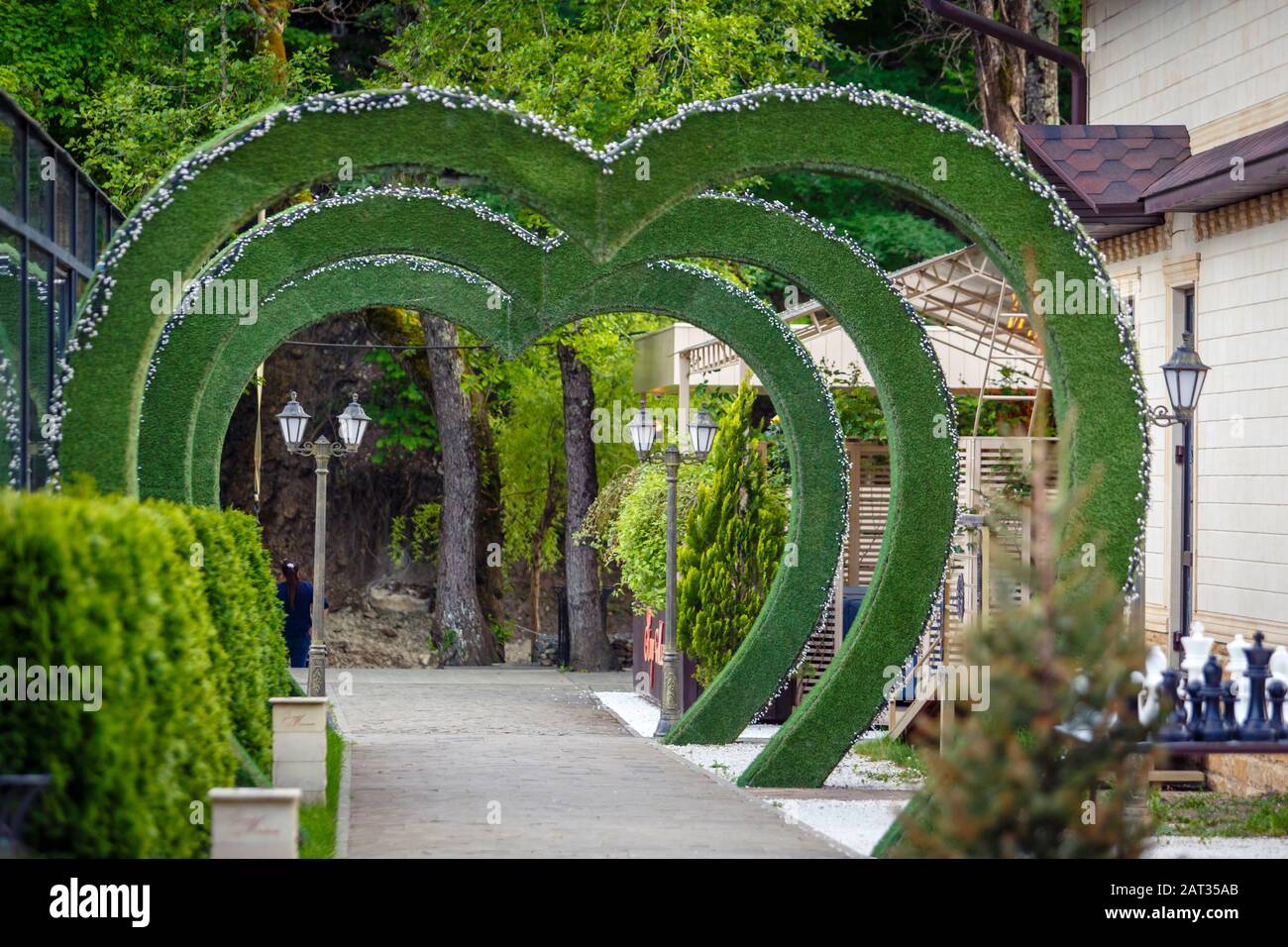 a path running through green arches in the shape of a heart. Stock Photo