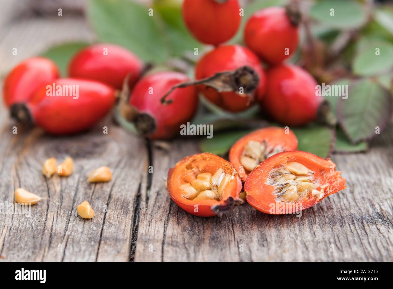 Red rose hips and ripened berries in half with seeds on old wooden
