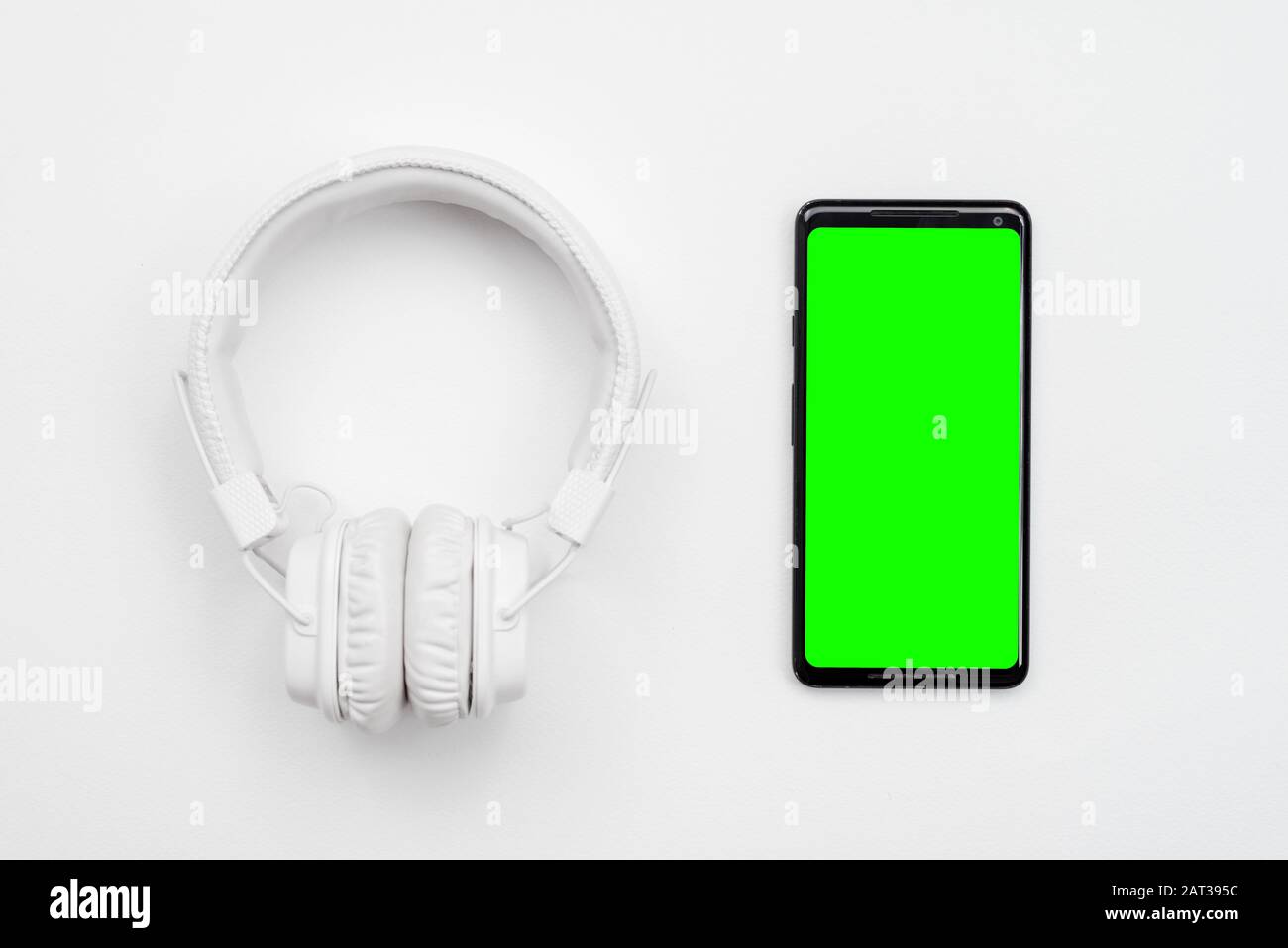 White wireless headphones and smartphone with green screen isolated on