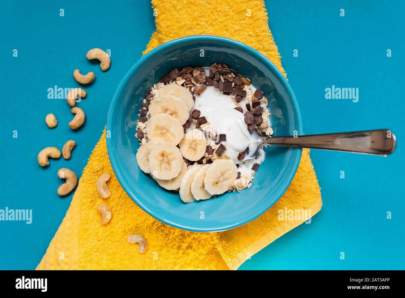 Bowl of healthy cereal with yogurt and bananas on a blue table Stock