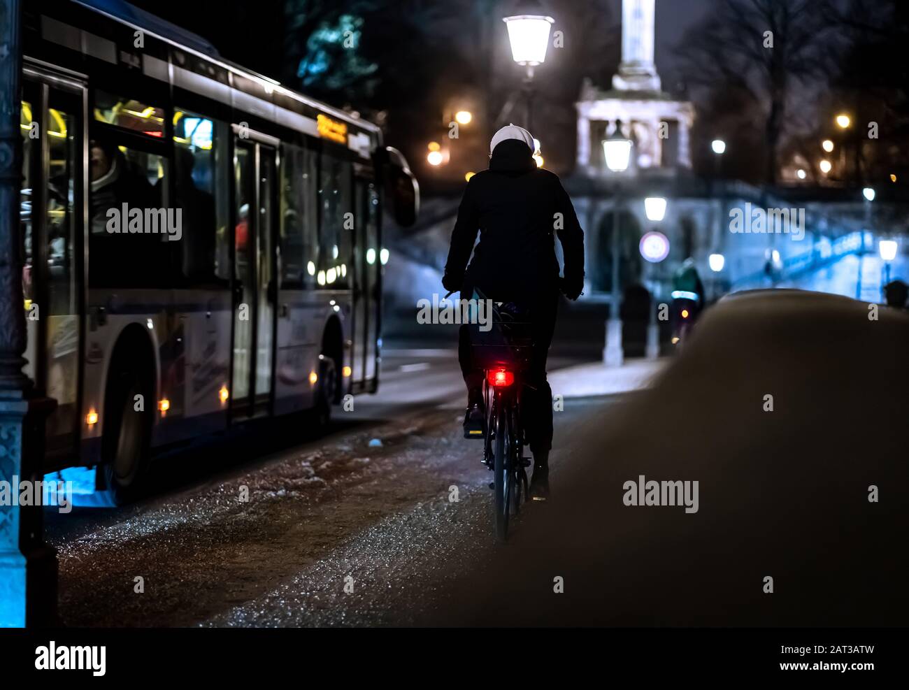 Cyclist riding alongside the bus in the illuminated city at night Stock ...