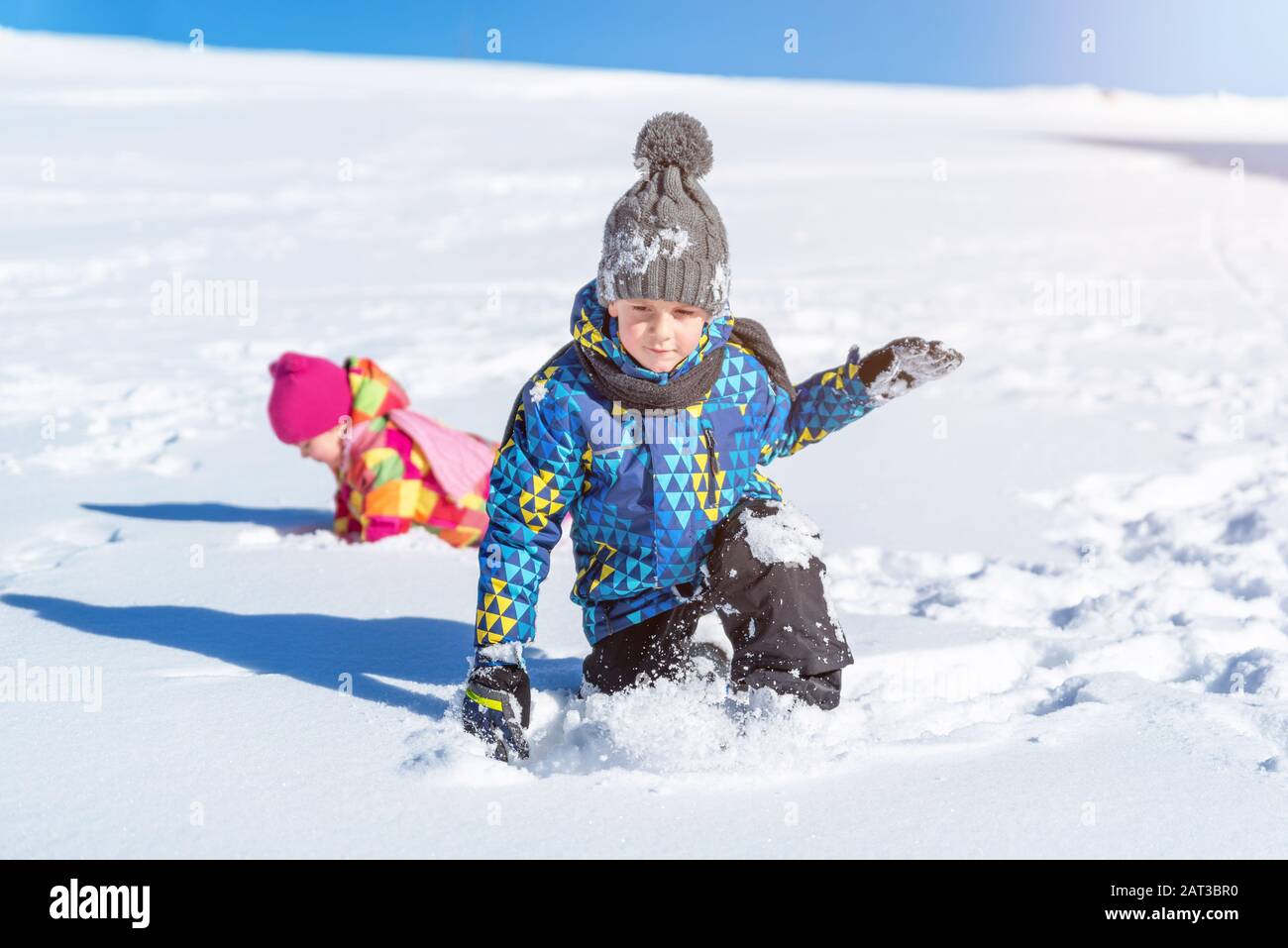 Boy comes out of the snow. Children's play and rolling in the snow. The concept of playing in the winter and improving children's health Stock Photo
