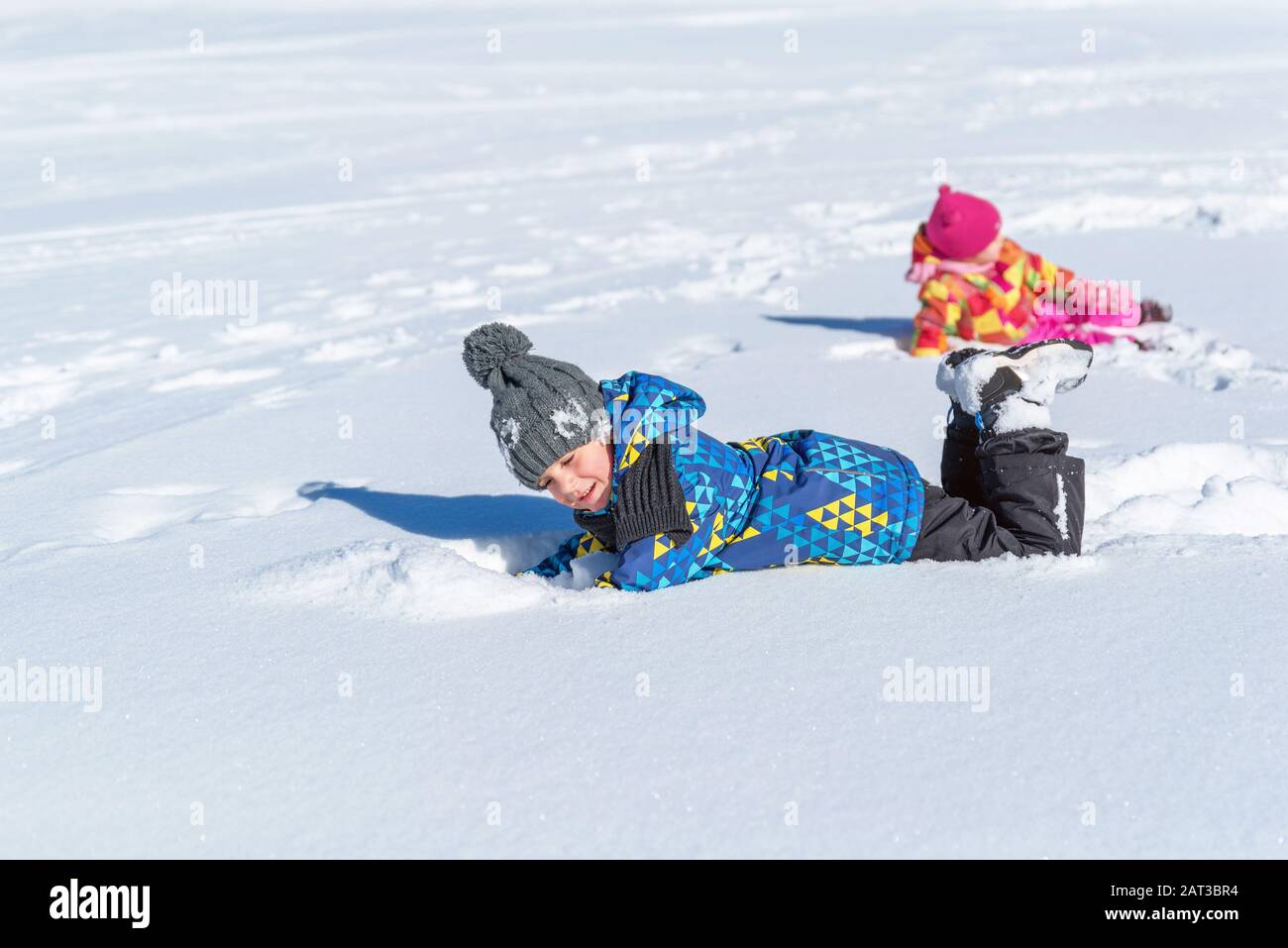 Boy and the girl are rolling in the snow. Concept of winter holidays and children's happiness and joy in the snow Stock Photo