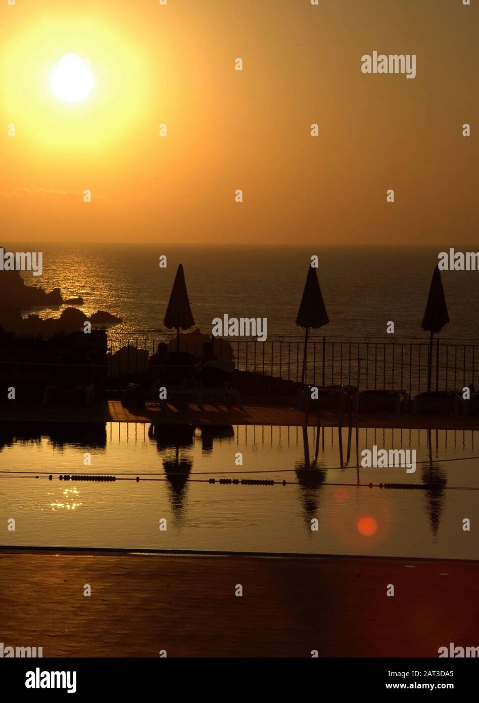 Beautiful scenery of the sunset reflecting on the swimming pool by the ...