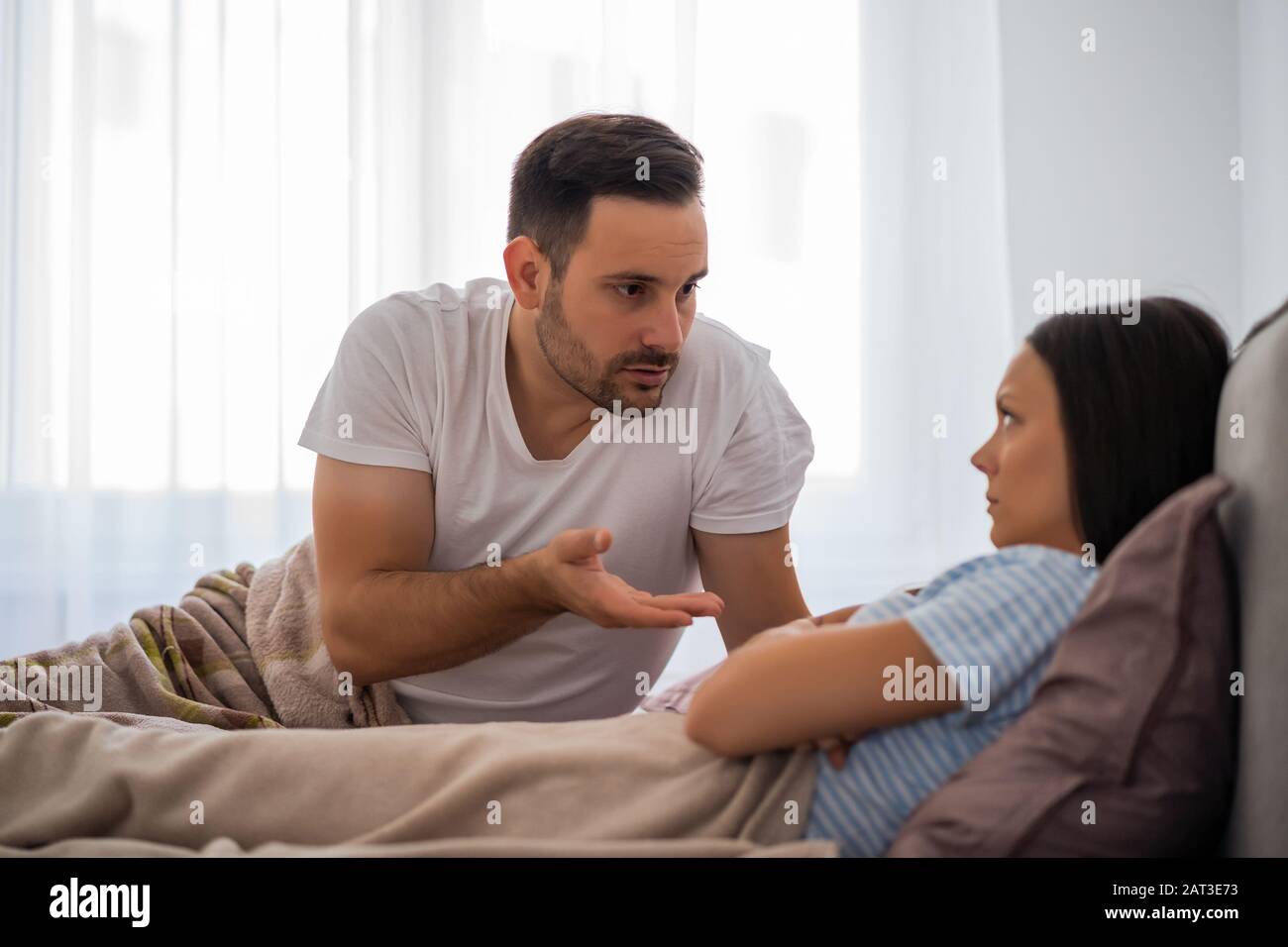 Couple is arguing in bed. Woman is offended and angry. Stock Photo