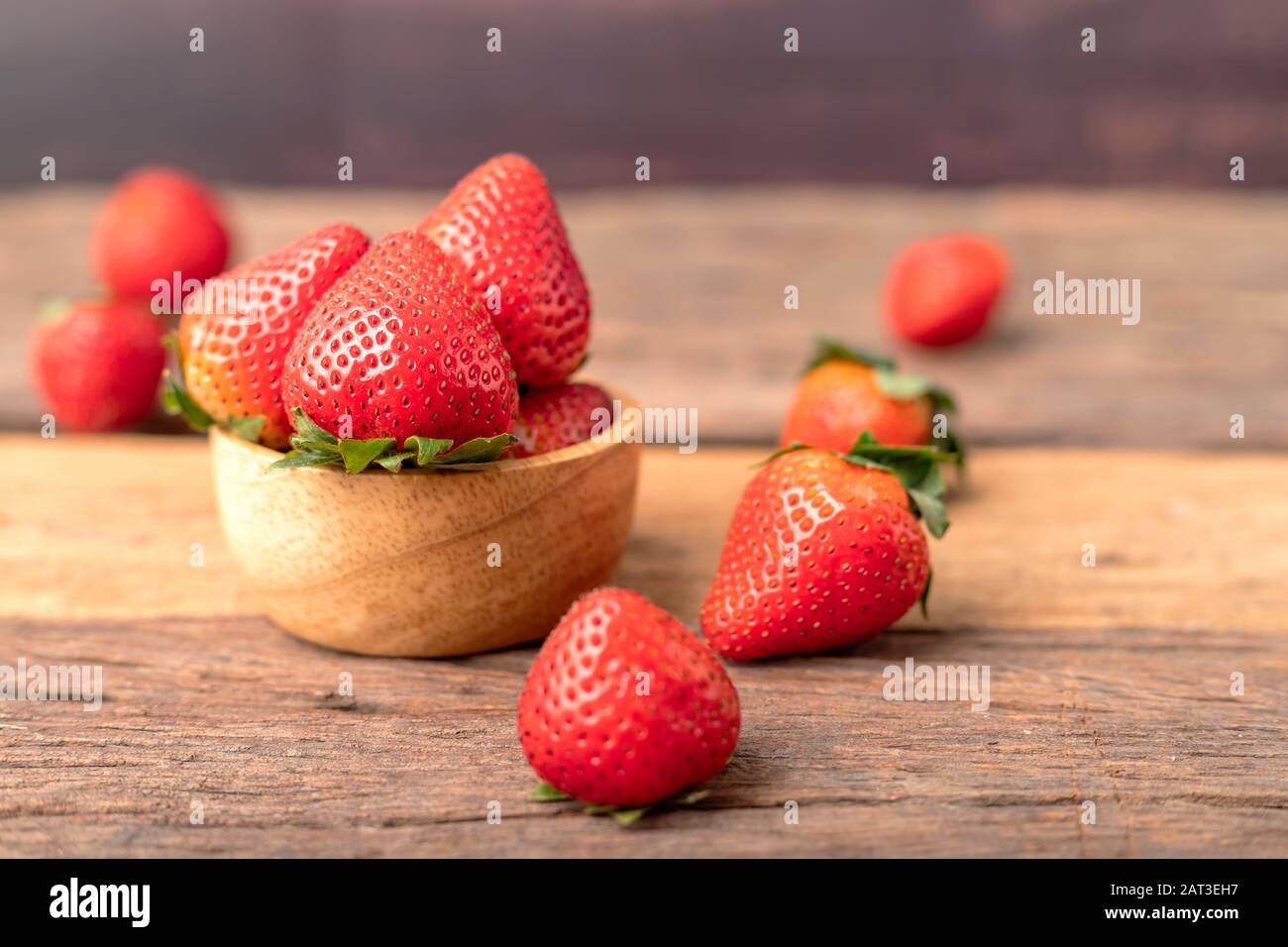 Freshness ripe strawberries are in a wooden bowl placed on the table. Stock Photo