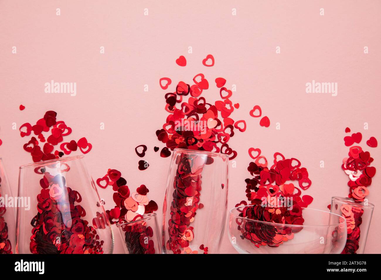 Valentine's day date night background. Drinks glasses with red heart confetti. Stock Photo