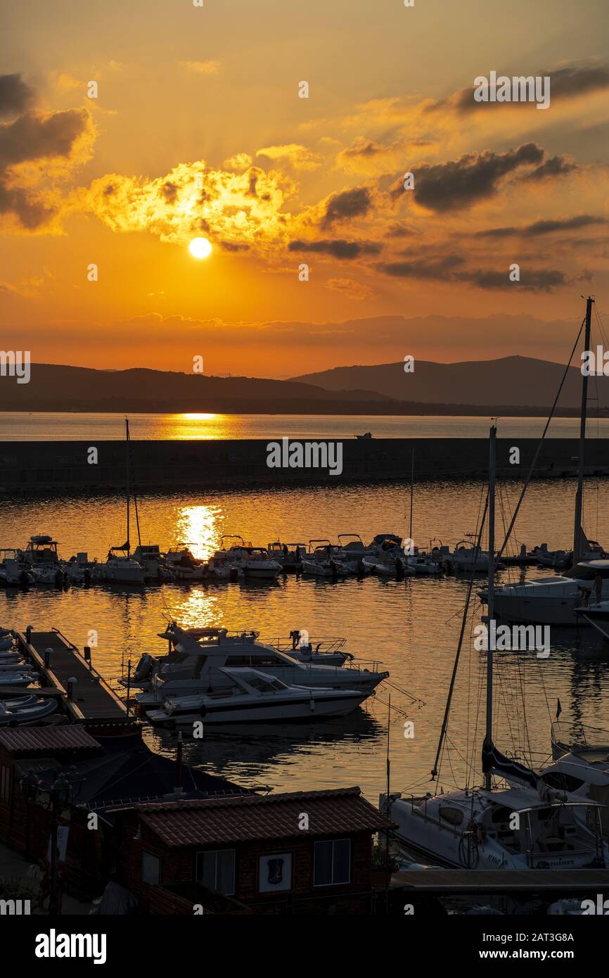 Alghero, Sardinia / Italy - 2018/08/10: Summer sunset skyline over the Alghero Marina yacht port at the Gulf of Alghero at Mediterranean Sea Stock Photo