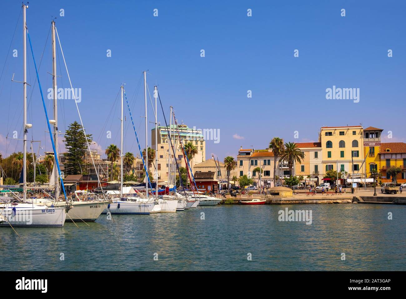 Alghero, Sardinia / Italy - 2018/08/10: Summer view of the Alghero Marina yacht port at the Gulf of Alghero at Mediterranean Sea with the Old Town quarter with historic defense walls Stock Photo