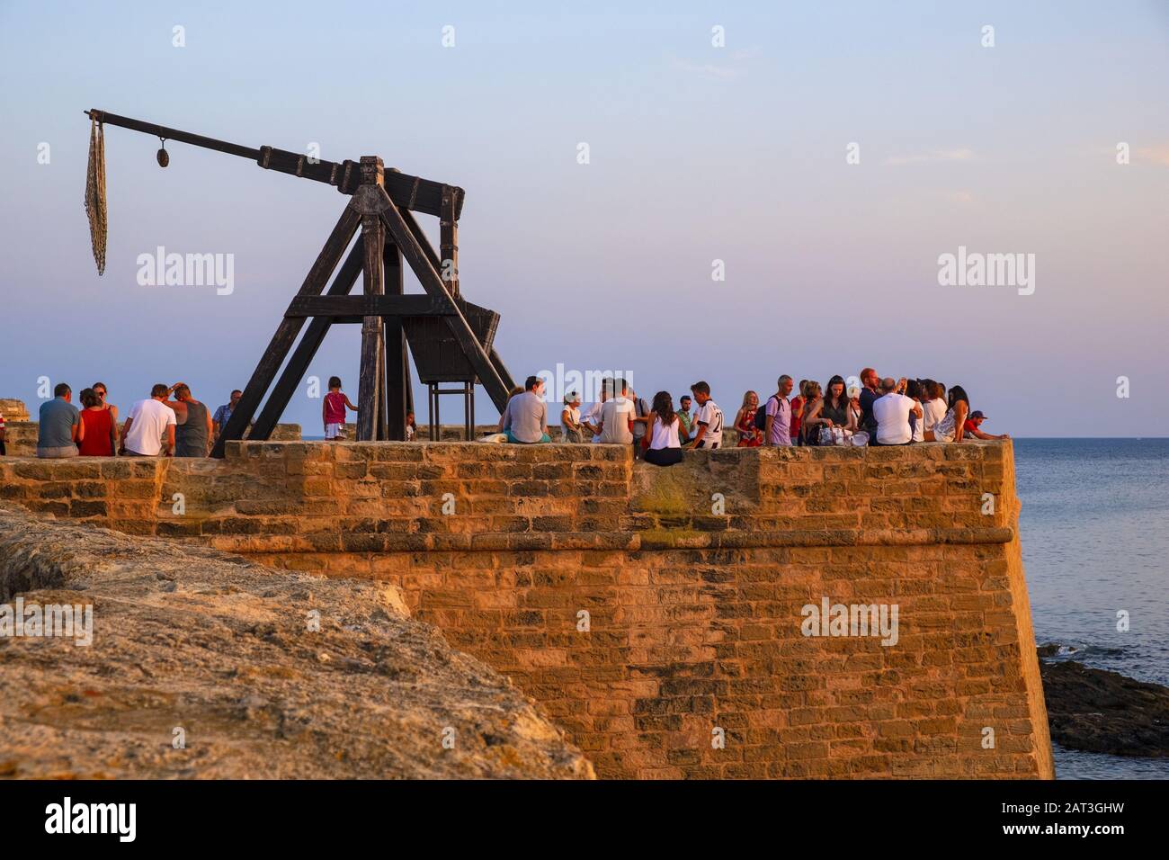 Alghero, Sardinia / Italy - 2018/08/10: Summer sunset view of the Alghero old town quarter with historic defense walls, fortifications and catapult construction Stock Photo