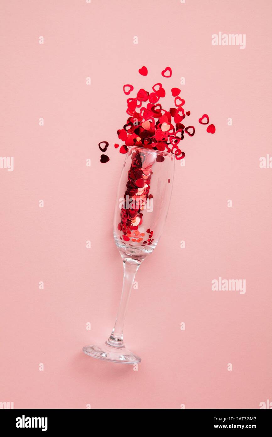 Valentine's day date night background. Drinks glasses with red heart confetti. Stock Photo