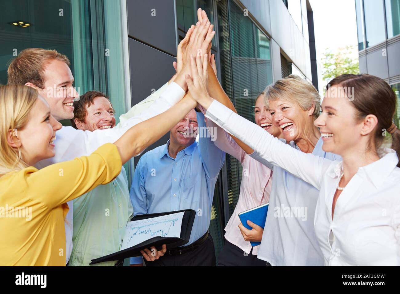 Successful business team giving high five in front of the office Stock ...