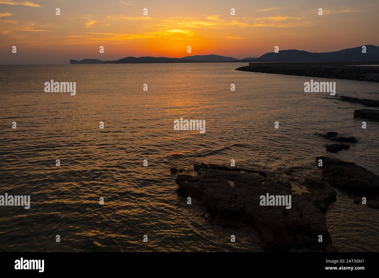 Summer sunset landscape over the Gulf of Alghero at Mediterranean Sea - Sardinia, Italy - with cliffs of Capo Caccia cape and Porto Conte Nature Reserve in background Stock Photo