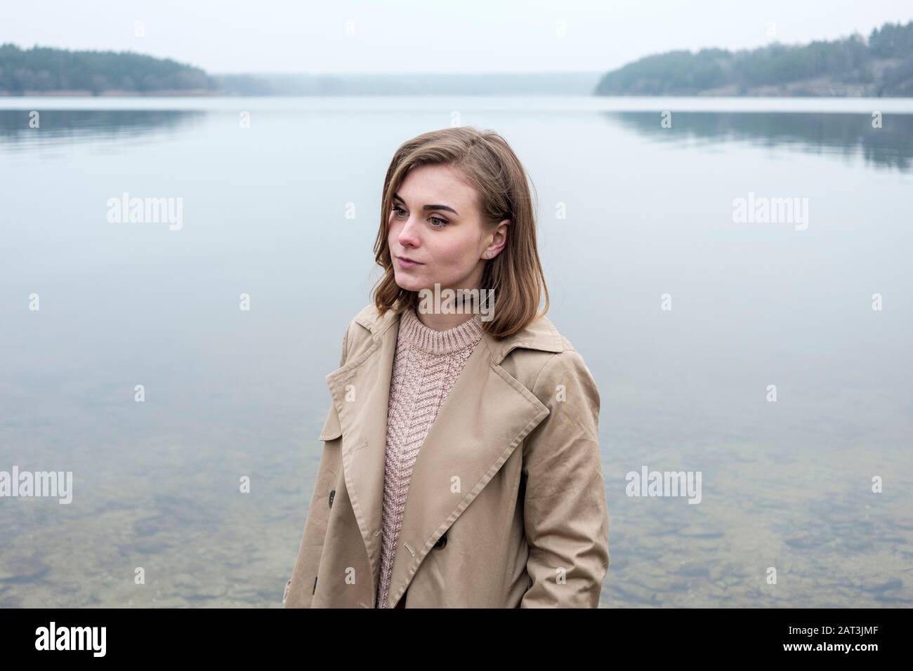 Beautiful young woman standing near a lake Stock Photo