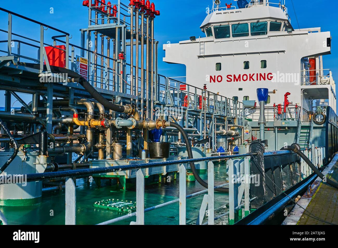 Bremerhaven, Germany, January 16., 2020: Structure and chaotic pipe system of a ship for receiving fossil fuels, with huge notice of the smoking ban a Stock Photo