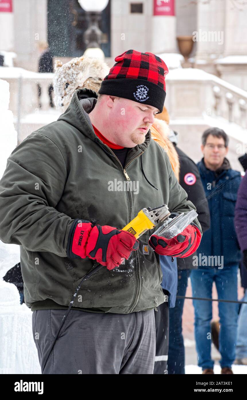 St. Paul, MN/USA - January 25, 2020: Ice sculptor at multi-block ice carving competition using grinding tool during annual winter carnival. Stock Photo