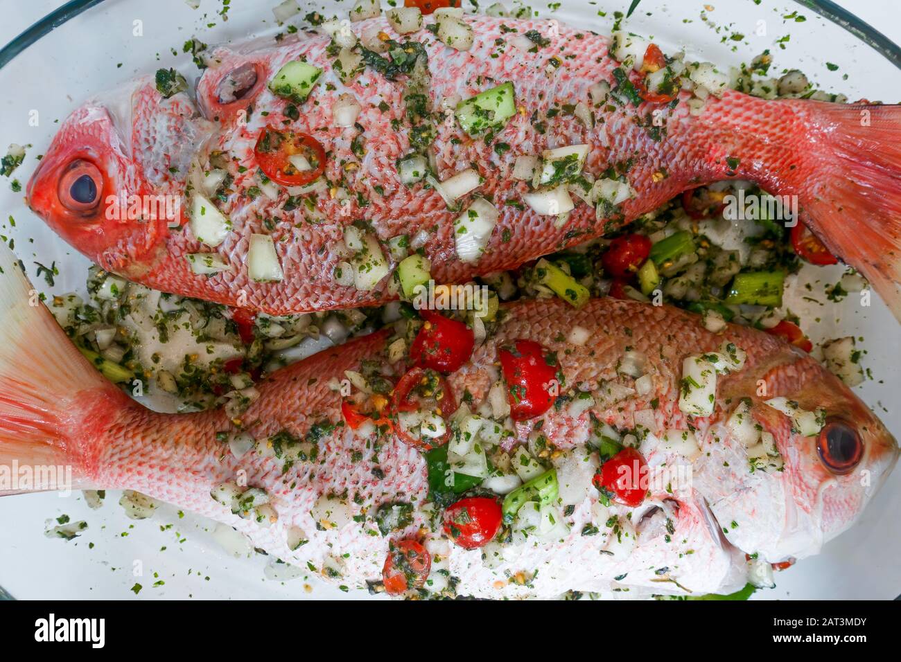 Two raw Red Snappers seasoned with onions, herbs and chillies Stock Photo