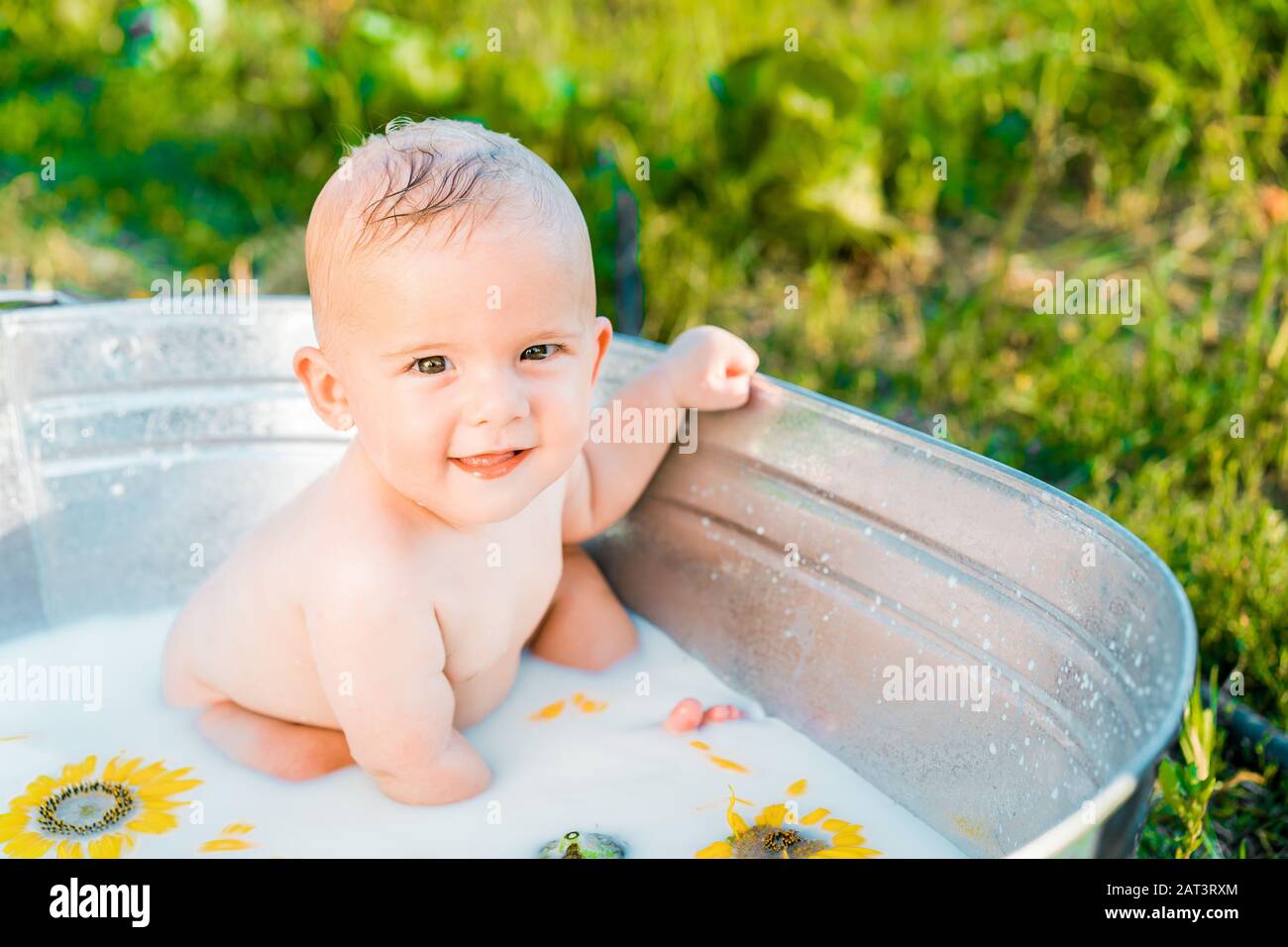 Cute little baby boy portrait in milk bath with sunflowers. Healthy