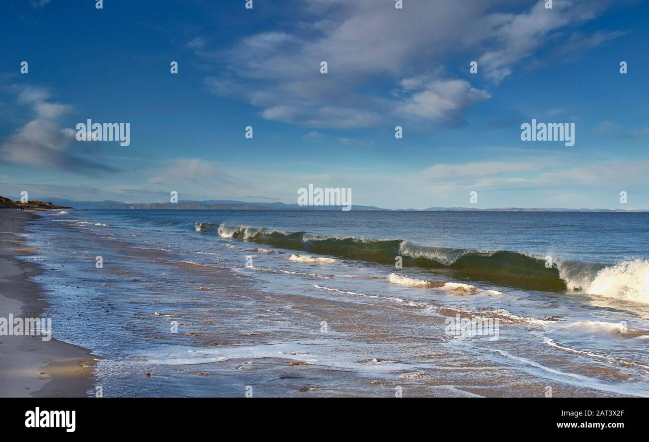 FINDHORN BEACH MORAY SCOTLAND GOLDEN SANDY BEACH BLUE SKY SEA AND A LARGE GREEN BREAKING WAVE Stock Photo
