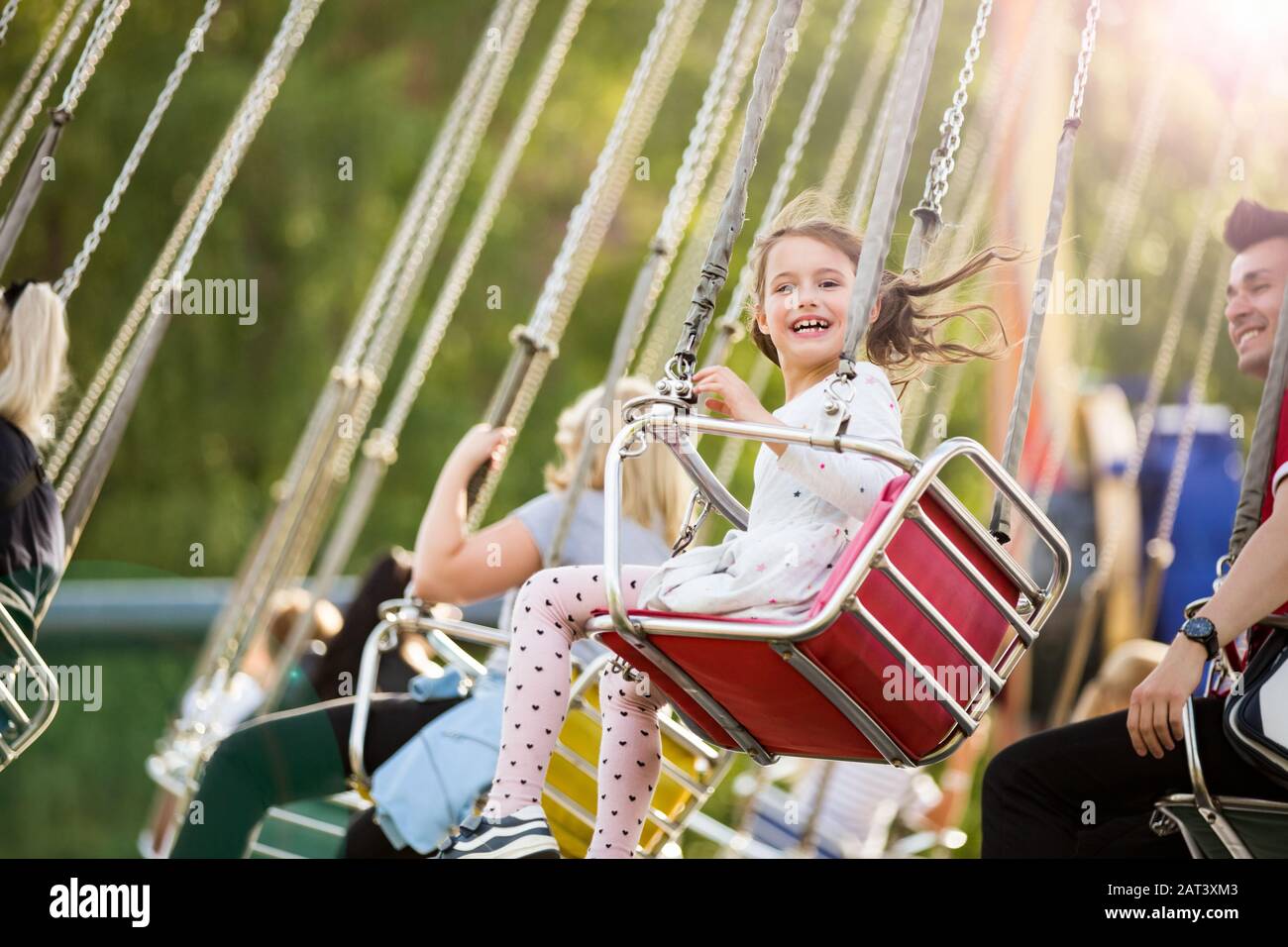 Little girl having fun on chain carousel. Happy summer memories. Carefree childhood and happiness Stock Photo