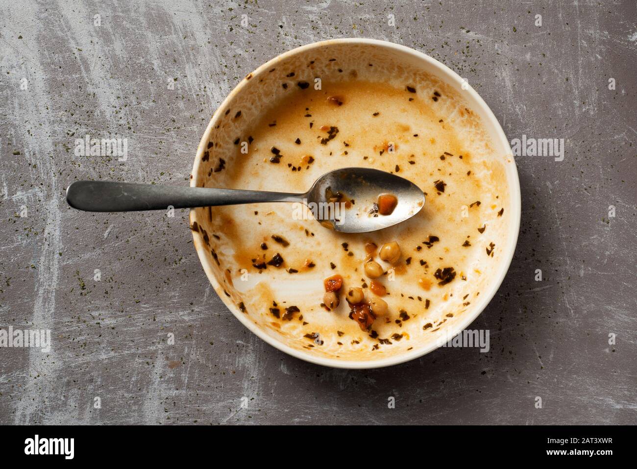 high angle view of a plate with the remains of a vegetarian chickpea stew on a rustic gray surface Stock Photo