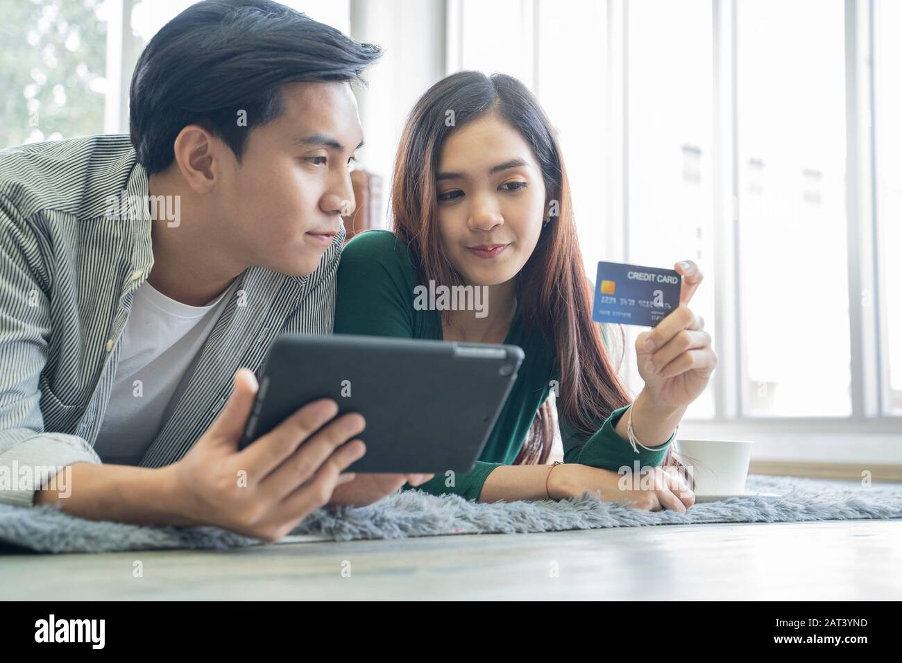 Couples help each other online shopping with credit cards. Stock Photo
