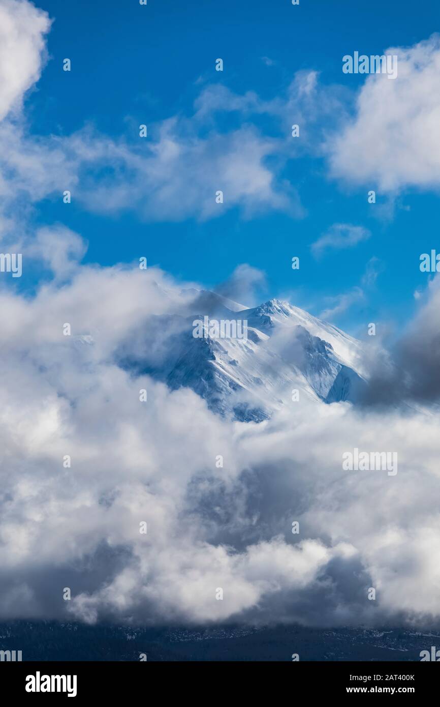 Mount Shasta glimpsed through scattered winter clouds, Shasta–Trinity National Forest, California, USA Stock Photo