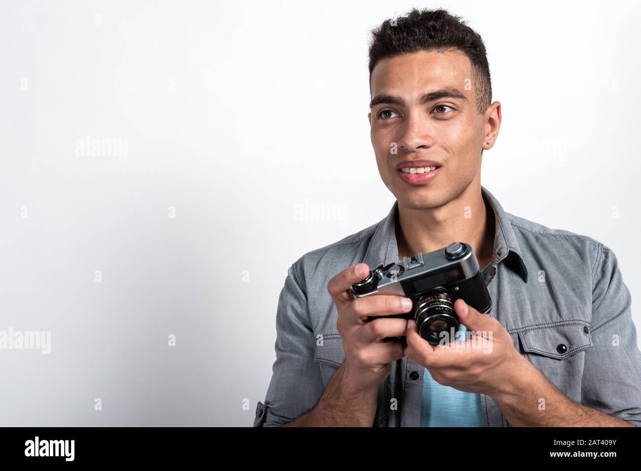 Portrait of happy mulatto man holding vintage photocamera. Touristic concept image. - Copy space Stock Photo