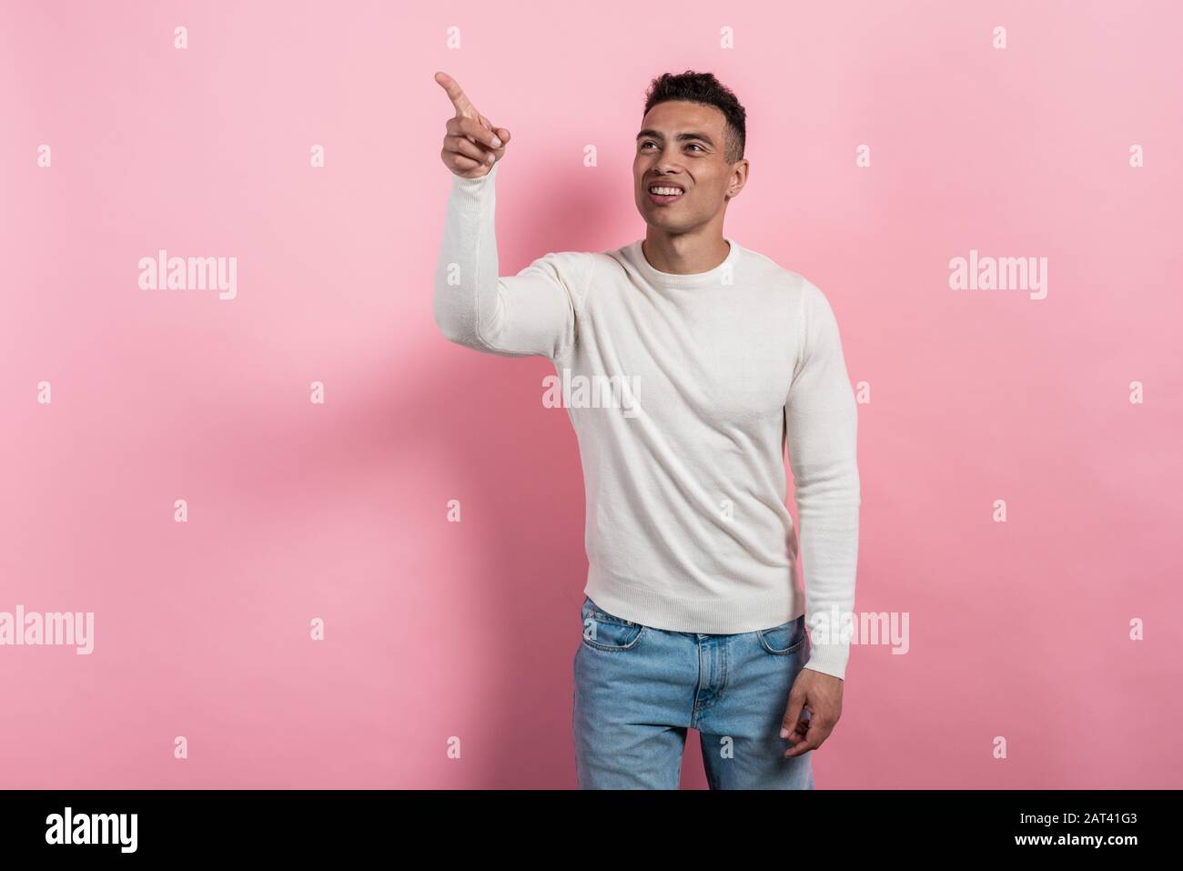 Happy mulatto man standing and pointing by his hand to a space. Copy space - Image Stock Photo