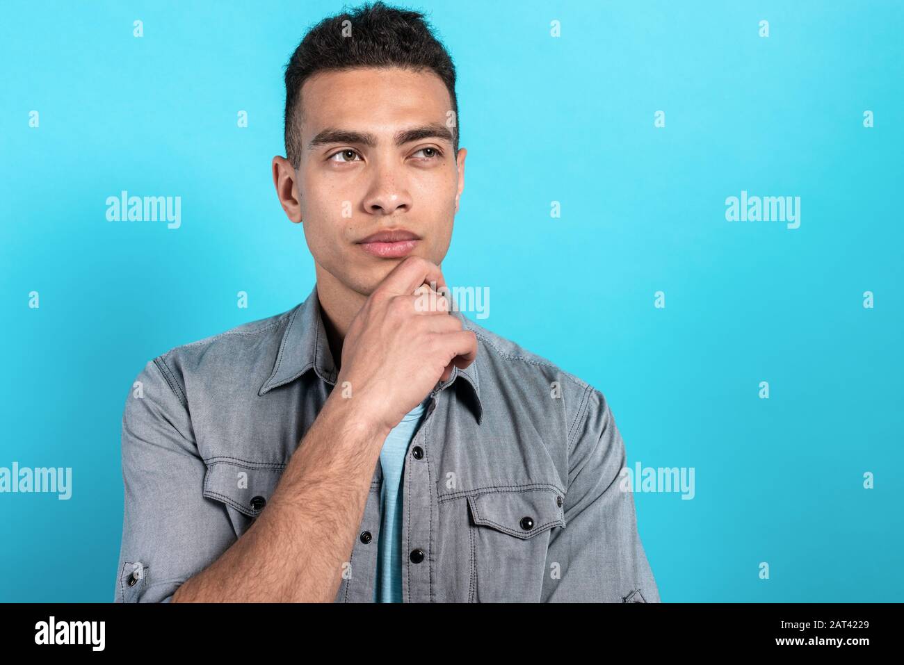 Handsome mulatto man looking dremly and touching his chin. Glance sideaway Stock Photo