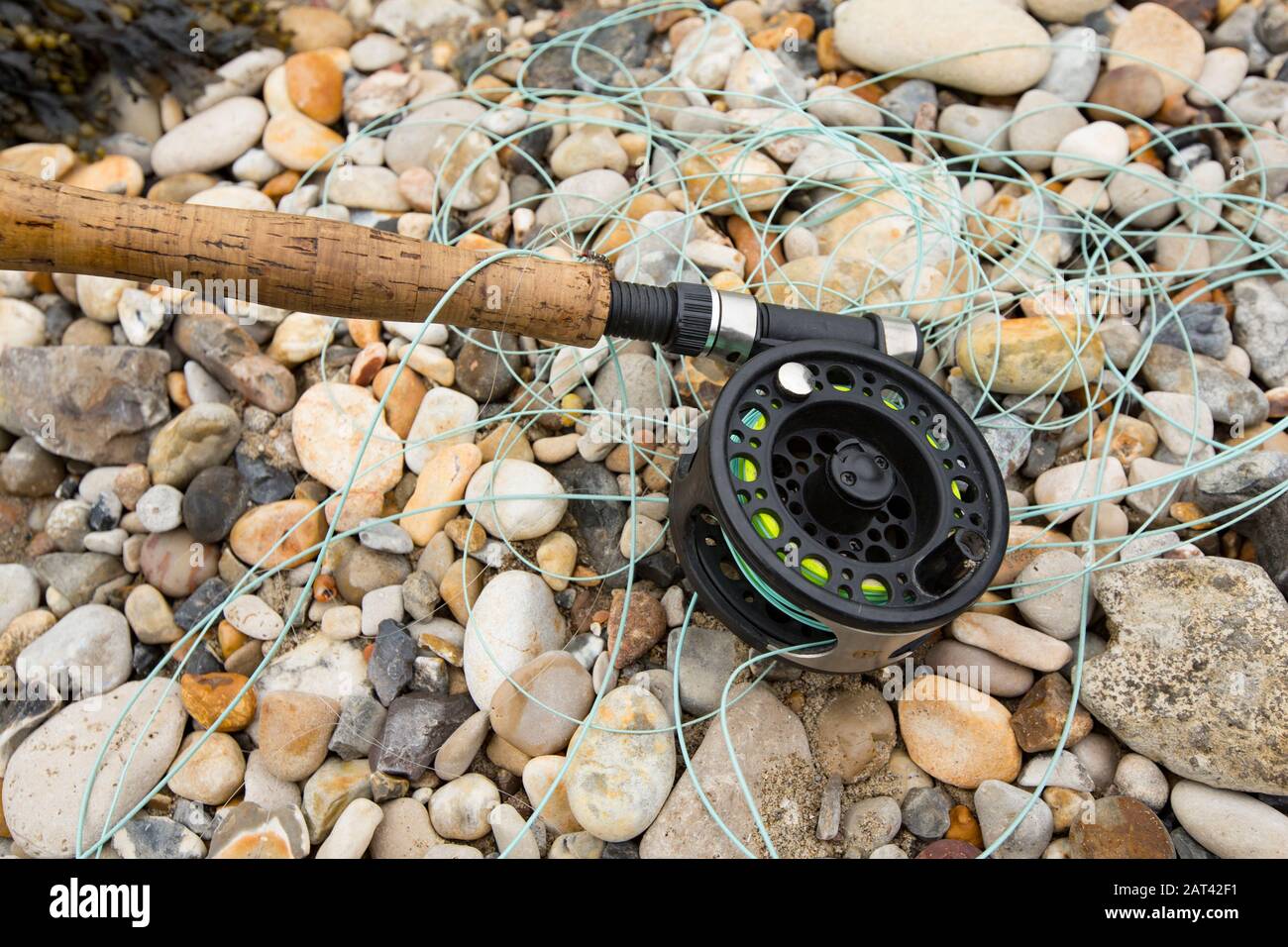A fly fishing rod and reel on the shore of Portland Harbour. Fly fishing for sea fish is a popular pastime and nearby are Ferrybridge and the Fleet la Stock Photo