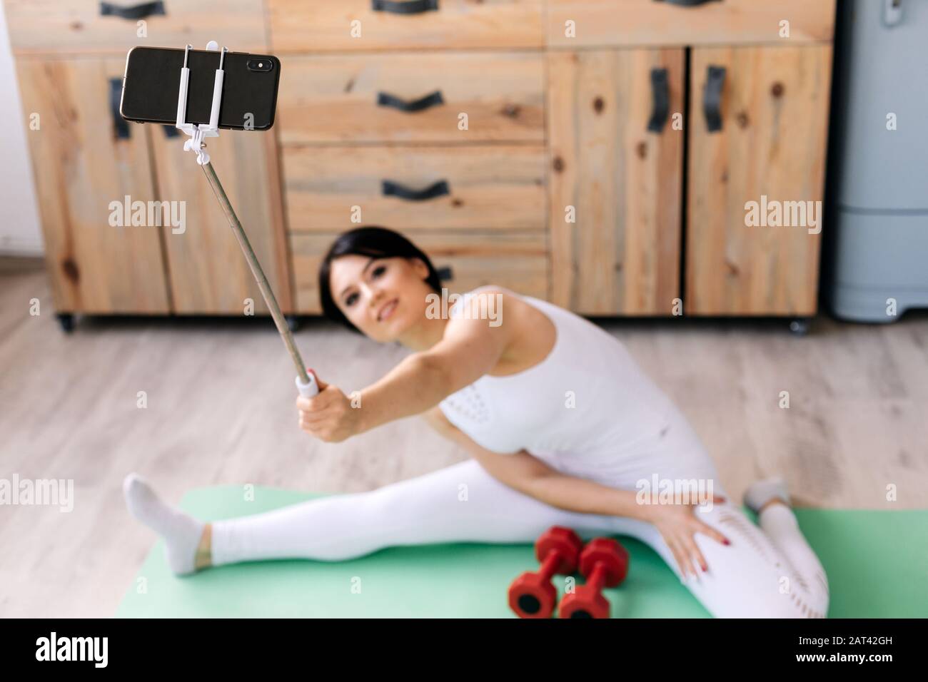 A girl takes a selfie while sitting on a string on a rug Stock Photo