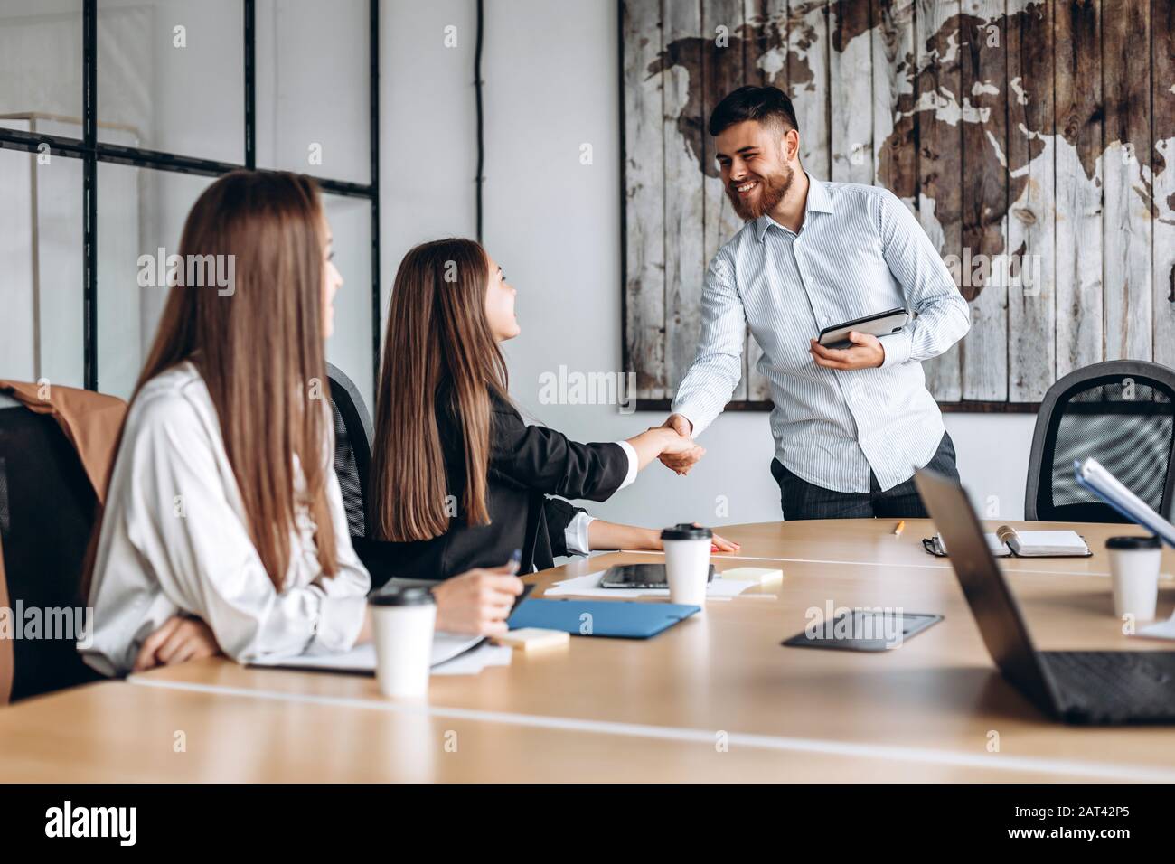Attractive guy with a beard shakes hands with the girl he works with in the office Stock Photo