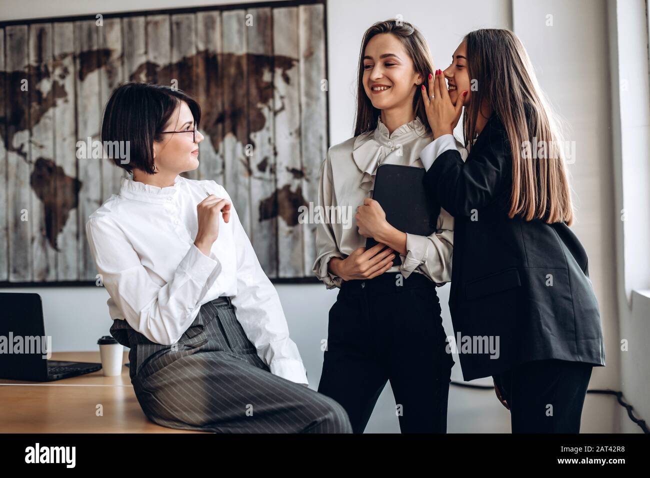 Beautiful businesswomen discuss and whisper to each other Stock Photo