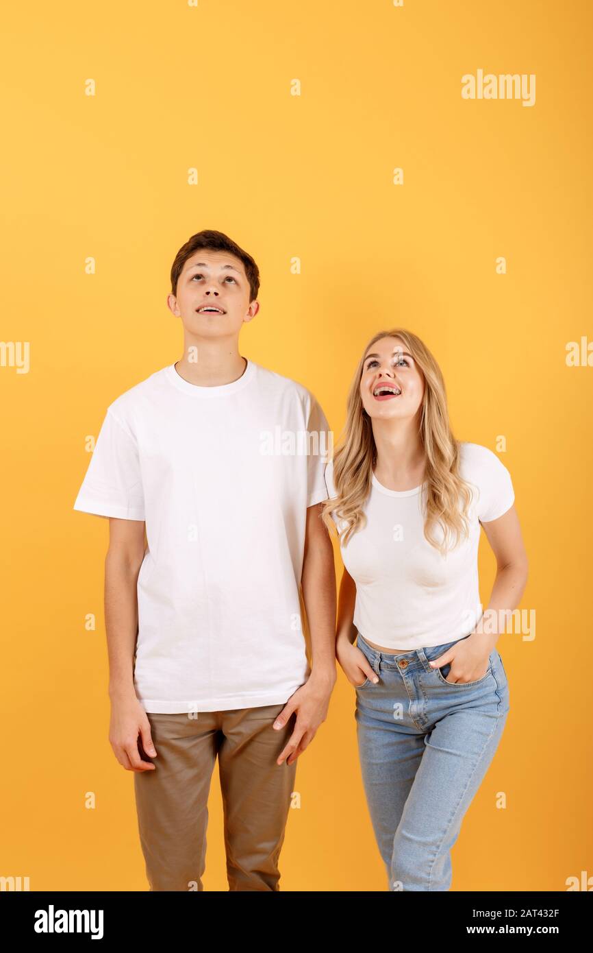 Happy emotional man and woman looking upwards at empty space, orange studio background Stock Photo