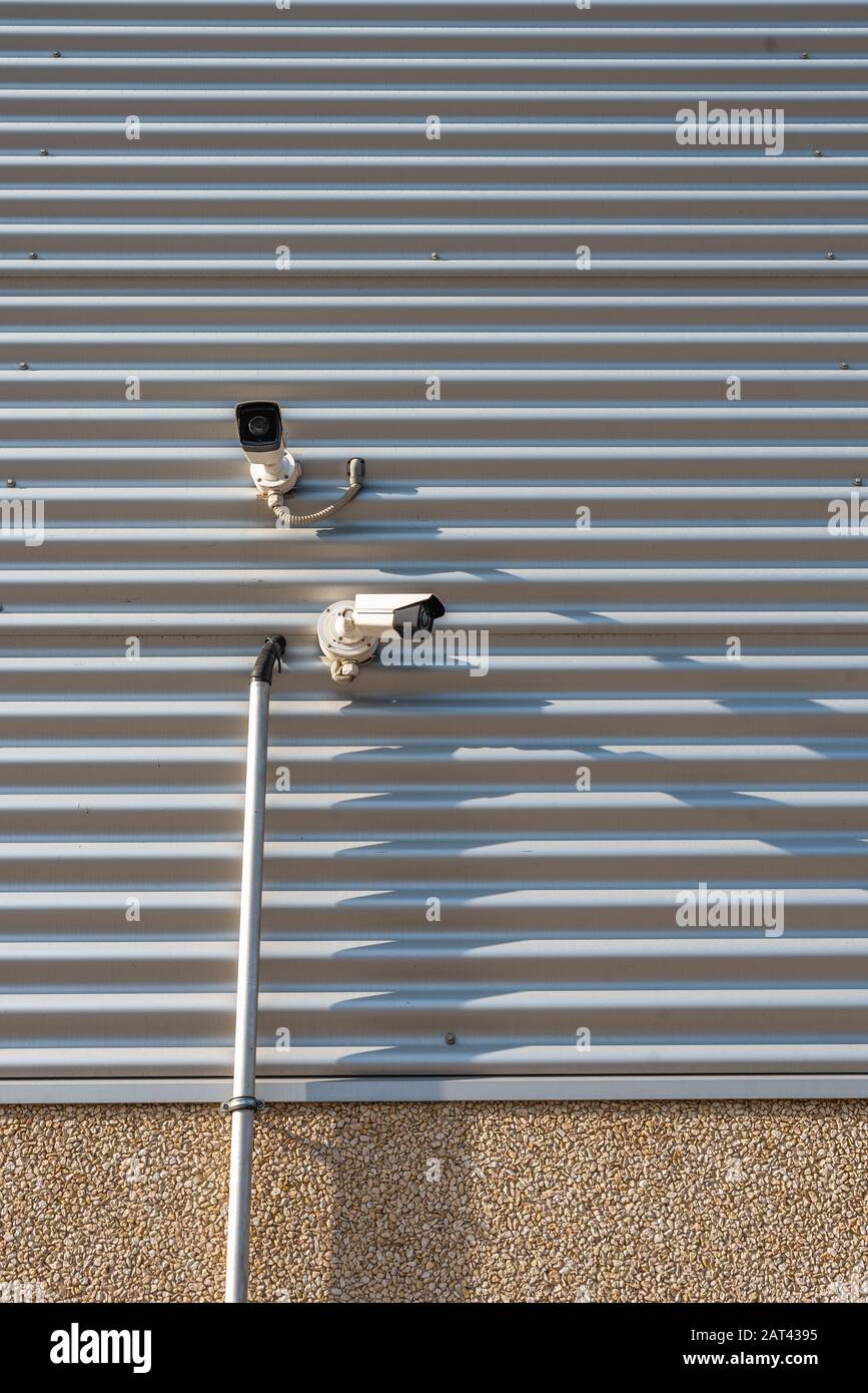 dual cctv cameras on wall shadows sunny day summer public spy watching  space for text Stock Photo - Alamy