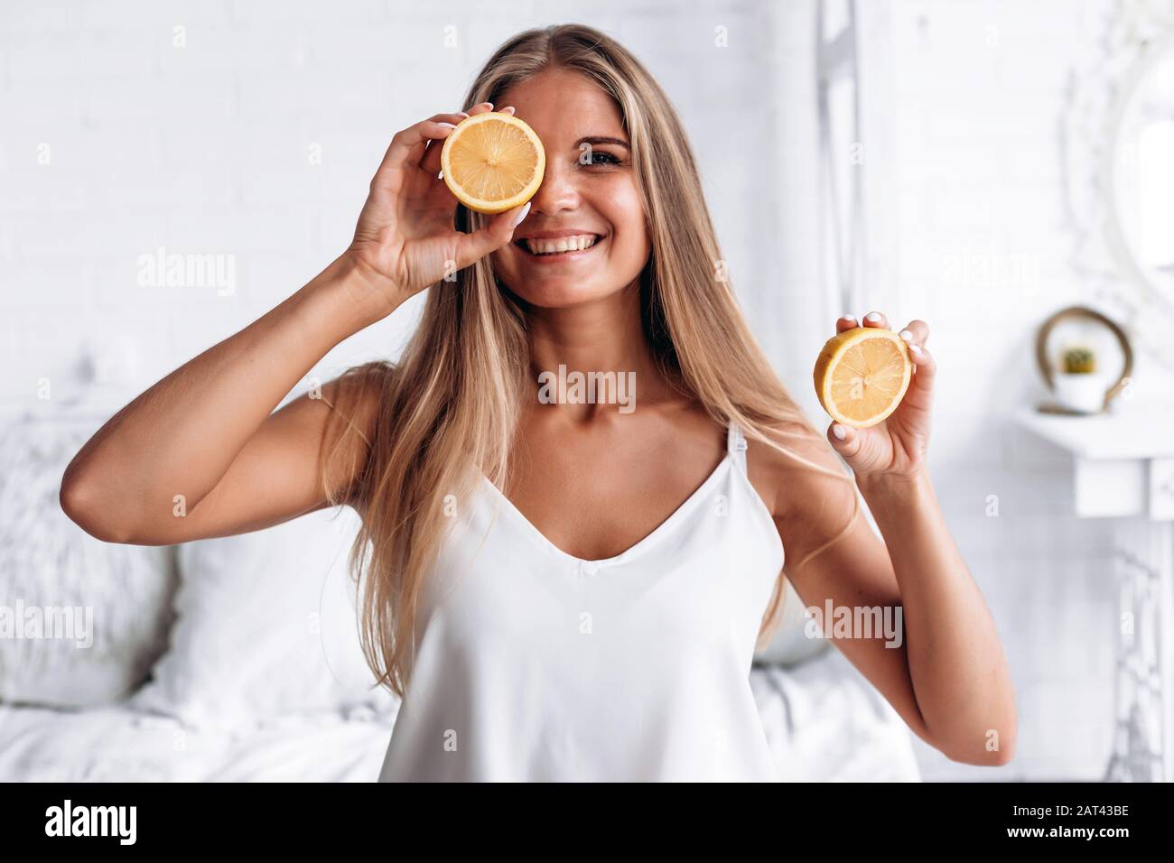 Beautiful blonde girl decides lemon in his hand and closes his eye Stock Photo