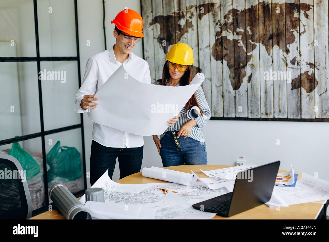 Architects in helmets looks at blueprint in office Stock Photo