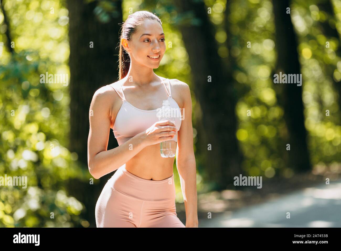 Happy brunette woman in sportwear holding a water bottle outdoor Stock ...