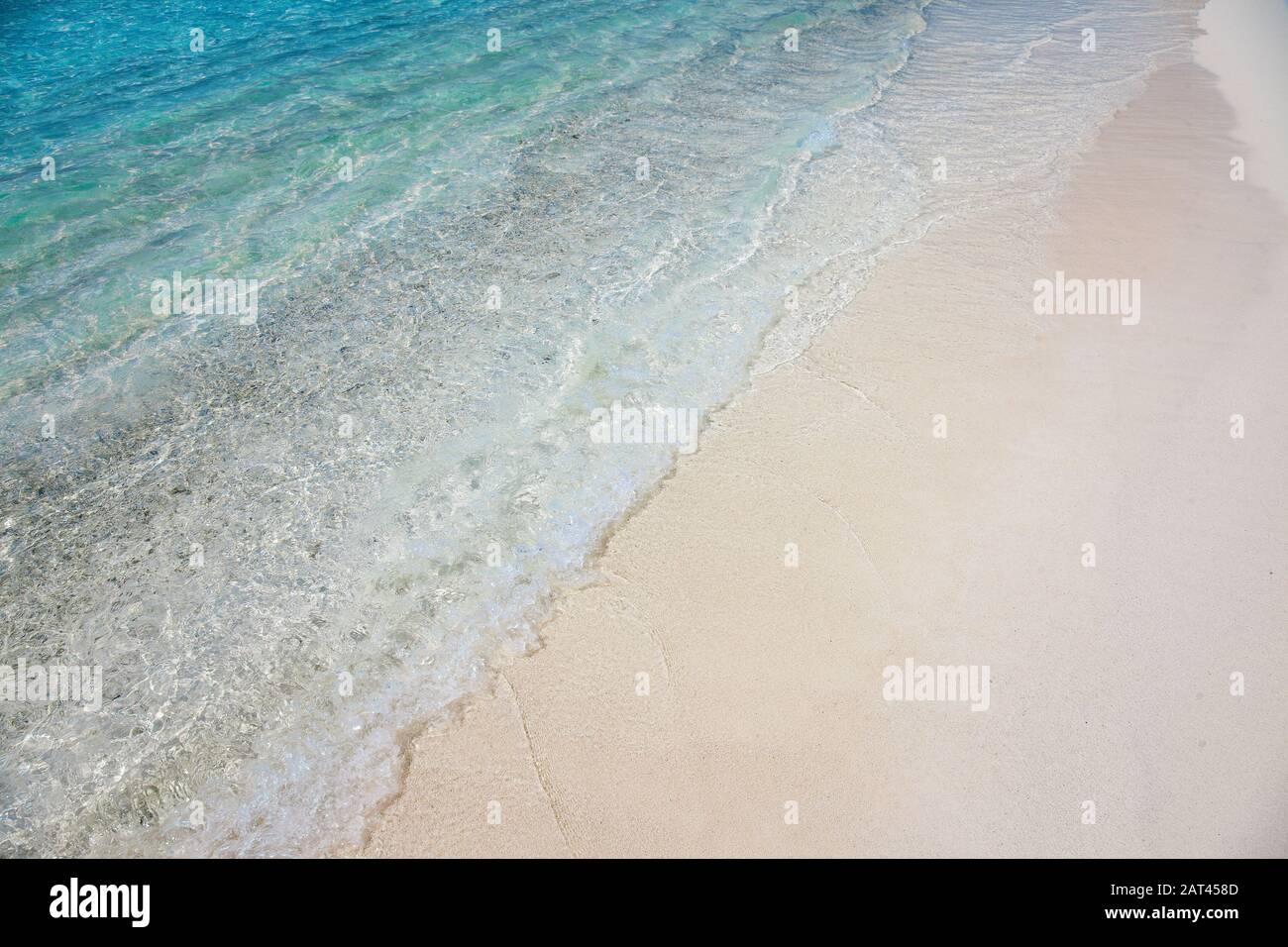 Sea shore sand and turquoise blue water wave Stock Photo