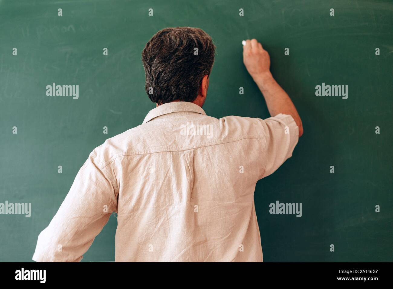 Teacher write on the blackboard and explain a lesson. Back view- Image ...
