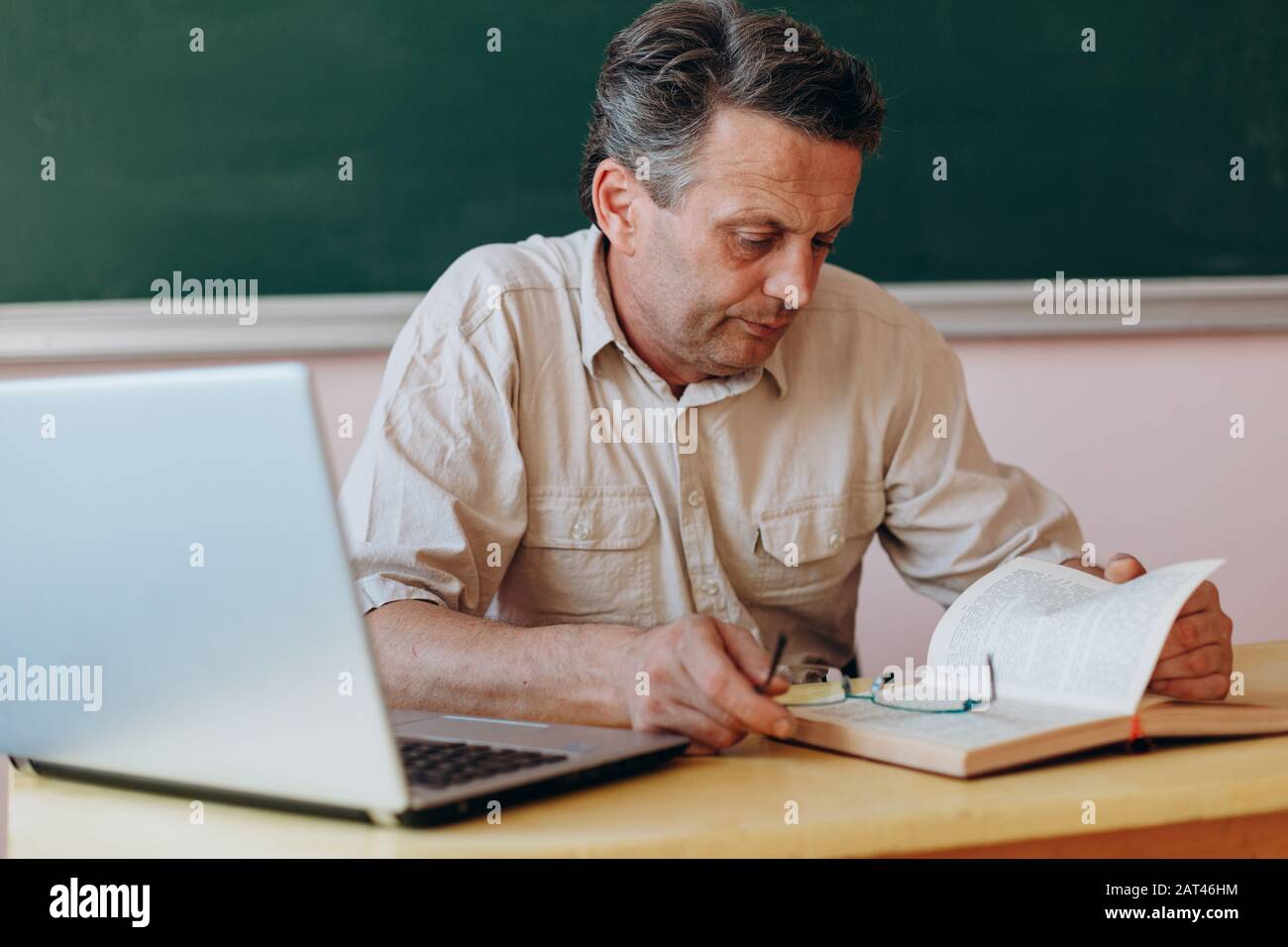Teacher attentively reading textbook . Image Stock Photo - Alamy
